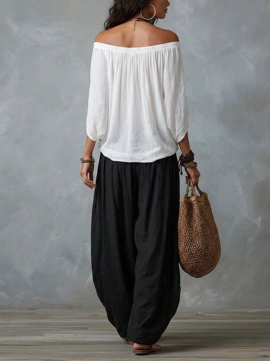 Conjunto de top blanco con hombros descubiertos y pantalón de pierna ancha.