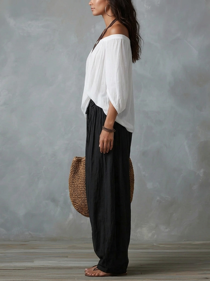 Conjunto de top blanco con hombros descubiertos y pantalón de pierna ancha.